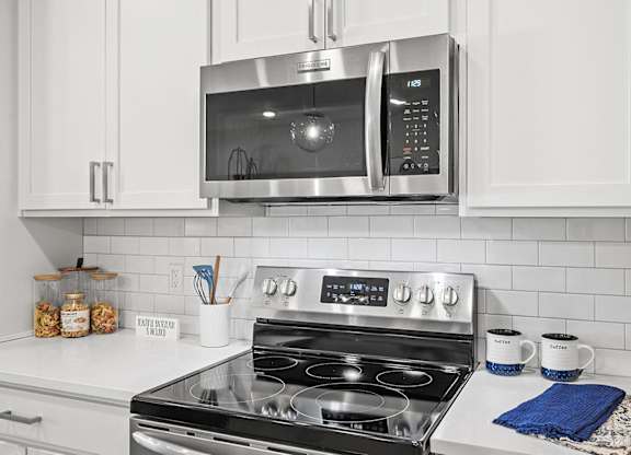 A modern kitchen with a stove top oven and microwave above it.