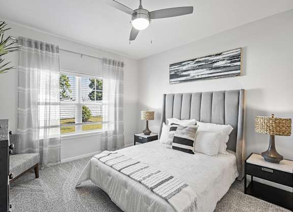 A bedroom with a large bed and a ceiling fan.