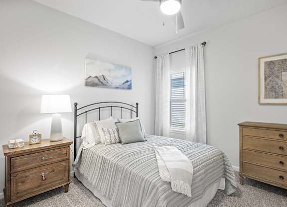 A bedroom with a bed, nightstand, and dresser.