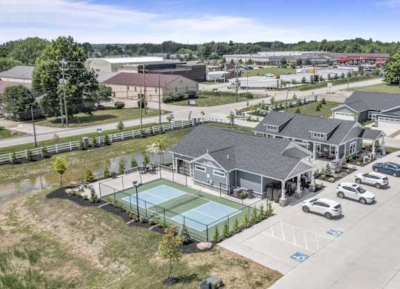 A tennis court is located in the middle of a parking lot.
