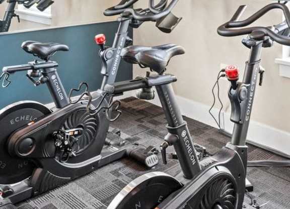Two stationary bikes are parked in a room.