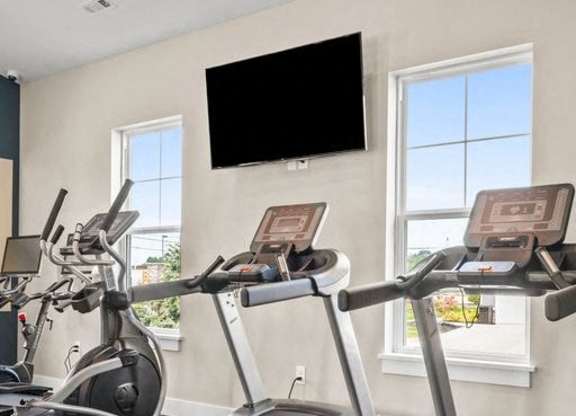 A treadmill with a TV mounted on the wall above it.