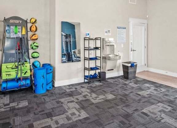 A room with a treadmill, exercise equipment, and a basket.