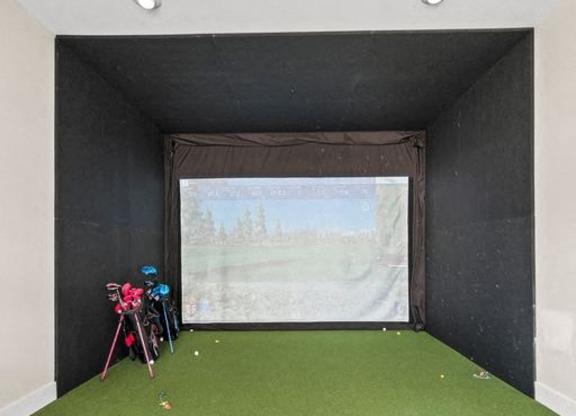 A room with a green carpet and a screen on the wall.