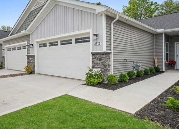 A house with a grey siding and a white garage door.
