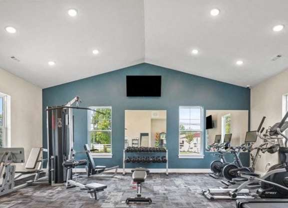 A spacious gym with a variety of equipment including treadmills, weights, and a television.