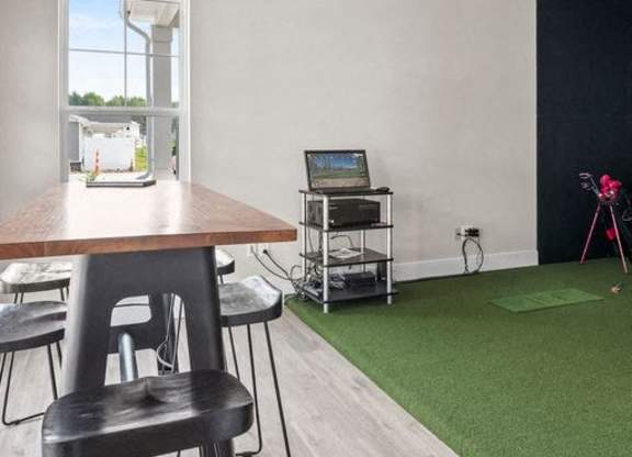 A room with a wooden table and chairs, a laptop, and a camera on a tripod.