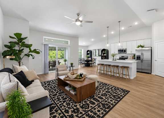 A modern living room with a white sofa, a coffee table, and a ceiling fan.