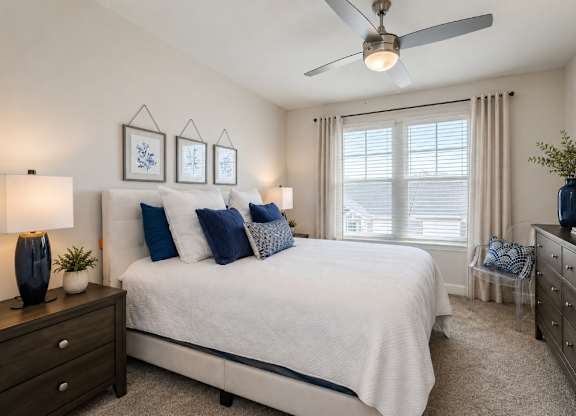 A bedroom with a bed, dresser, and ceiling fan.