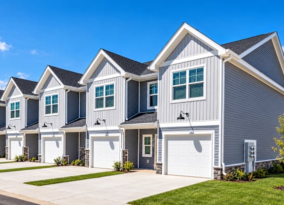 A row of houses with garages and driveways.