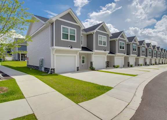 A row of houses with a sidewalk in front.