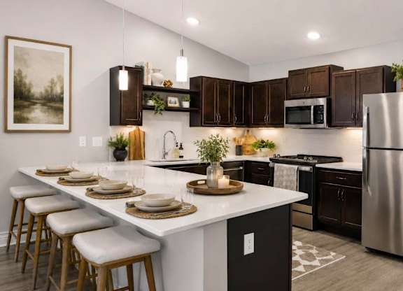 A modern kitchen with a white island and dark brown cabinets.
