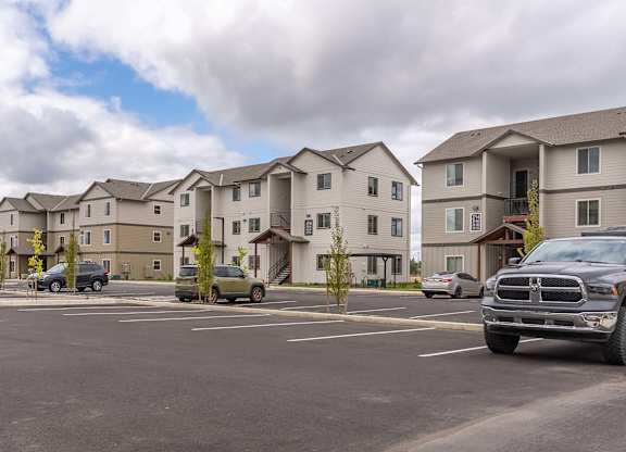 A parking lot with cars and apartment buildings in the background at Marcola Apartment Homes, Forest Grove, 97477