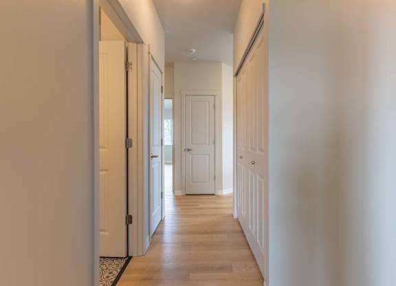 A long hallway with white doors and a wooden floor at Marcola Apartment Homes, Forest Grove, Oregon