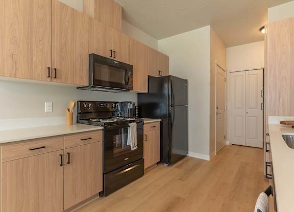 A kitchen with wooden cabinets and black appliances at Marcola Apartment Homes, Forest Grove, Oregon