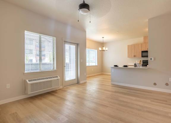 A spacious kitchen and living room with wooden floors and white walls at Marcola Apartment Homes, Forest Grove, 97477