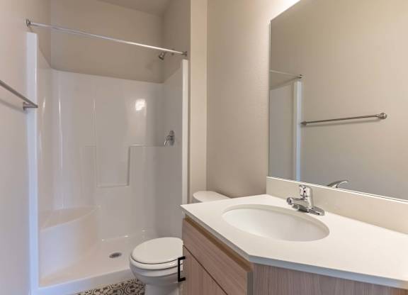 A white sink is on a countertop next to a toilet at Marcola Apartment Homes, Forest Grove, Oregon