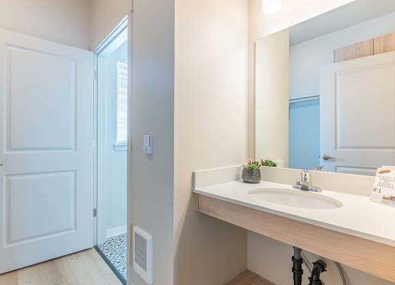 A bathroom with a white door, sink, and mirror at Marcola Apartment Homes, Oregon