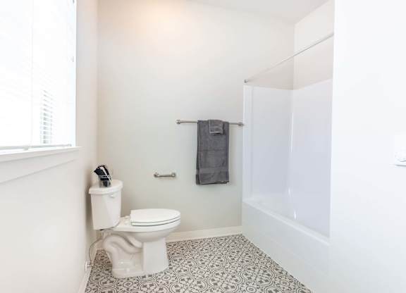 A white toilet sits in a bathroom with a white wall and a white floor at Marcola Apartment Homes, Oregon, 97477
