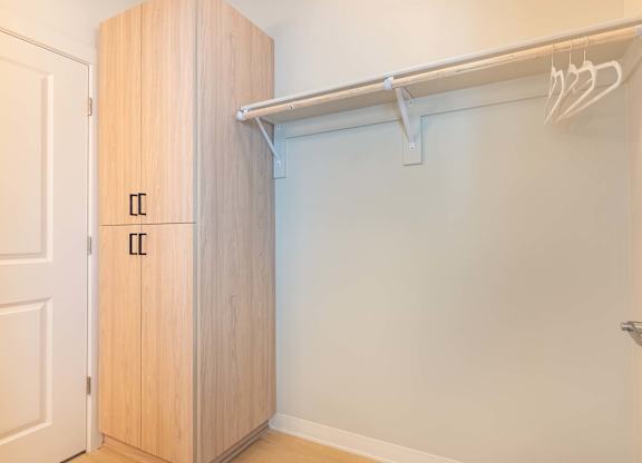 A white closet with a wooden door and a white shelf at Marcola Apartment Homes, Forest Grove