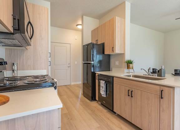 A kitchen with a black refrigerator and wooden cabinets at Marcola Apartment Homes, Forest Grove, 97477
