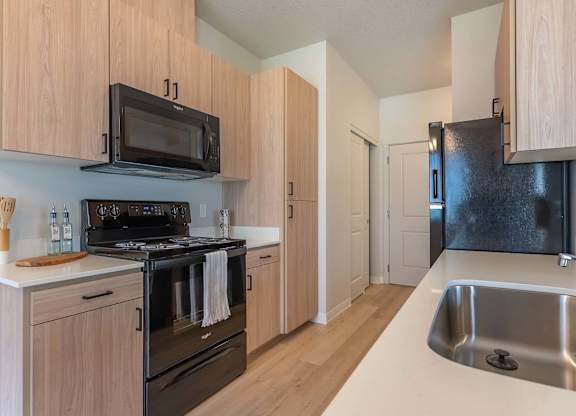 A kitchen with wooden cabinets and a black stove top oven at Marcola Apartment Homes, Forest Grove, OR