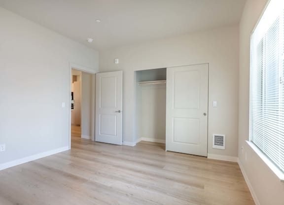 A room with white walls and wooden flooring with three doors at Marcola Apartment Homes, Forest Grove, Oregon