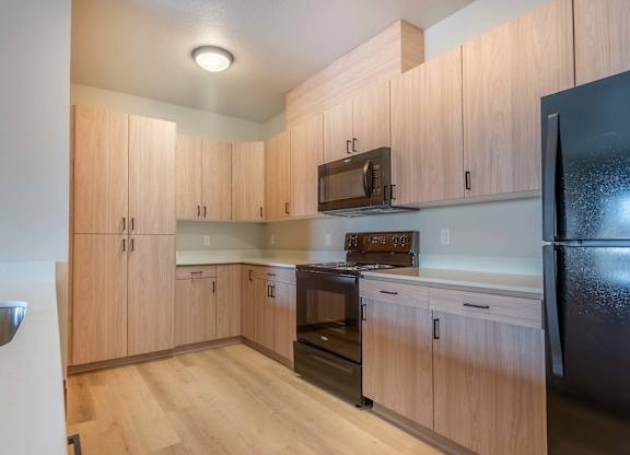 A kitchen with wooden cabinets and black appliances at Marcola Apartment Homes, Forest Grove, OR, 97477