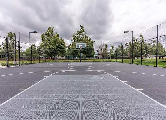 A basketball court is surrounded by a fence and has a basketball hoop in the middle at Marcola Apartment Homes, Oregon, 97477