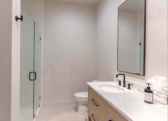 A white bathroom with a sink, toilet, and a mirror at Westgate Apartment Homes, Oregon, 97801