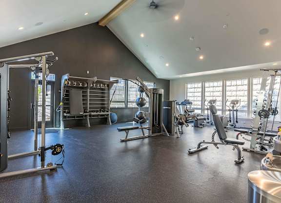 A spacious gym with a variety of equipment including a squat rack, bench, and weights at Westgate Apartment Homes, Pendleton, OR, 97801