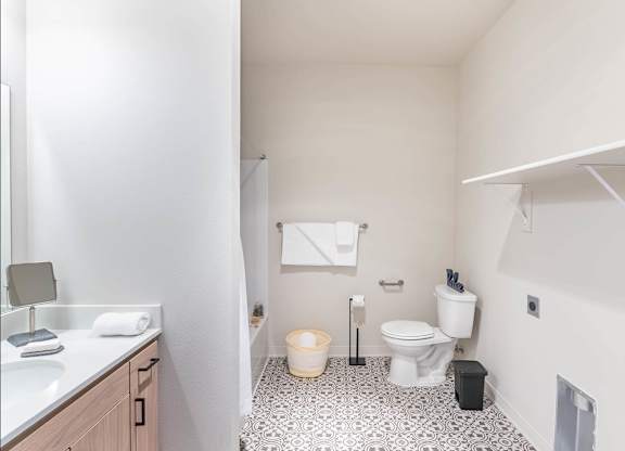 A bathroom with a toilet, sink, and a trash can at Westgate Apartment Homes, Pendleton, 97801