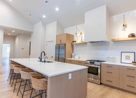 A modern kitchen with a long white island and stainless steel appliances at Westgate Apartment Homes, Oregon, 97801