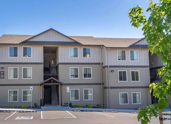 A large, modern building with a parking lot in front at Westgate Apartment Homes, Pendleton