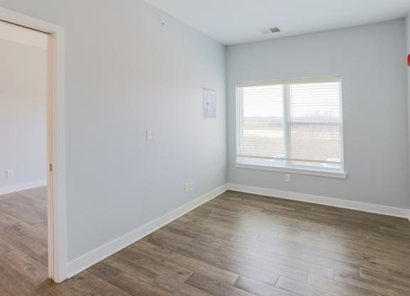 A room with a wooden floor and a window with blinds.