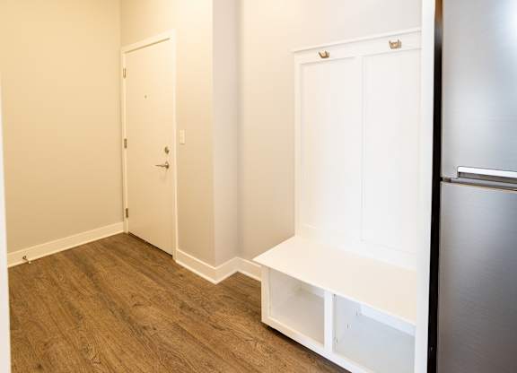 A kitchen with a refrigerator, a door, and a shelf.