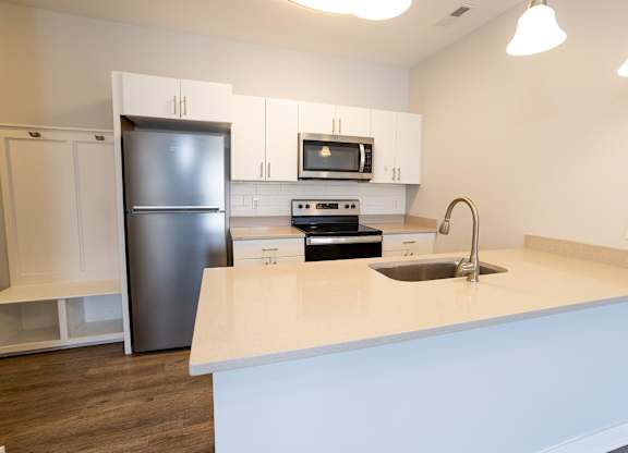 A kitchen with a white counter top and a black refrigerator.