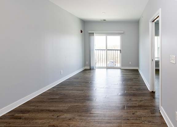 A long, empty room with wooden floors and white walls.