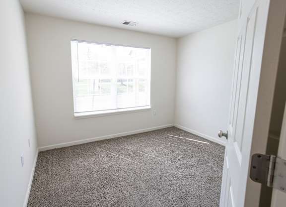 A room with a carpeted floor and a window.
