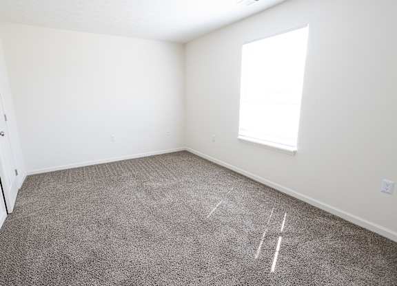 A room with a carpeted floor and a window.