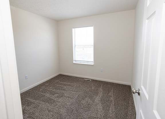 A room with a carpeted floor and a window.