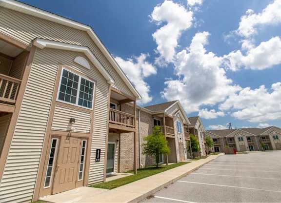 A row of apartment buildings with a parking lot in front.