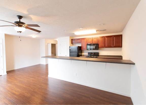 A kitchen with brown cabinets and a black refrigerator.
