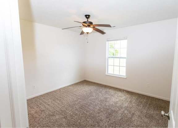 A room with a ceiling fan and a window.