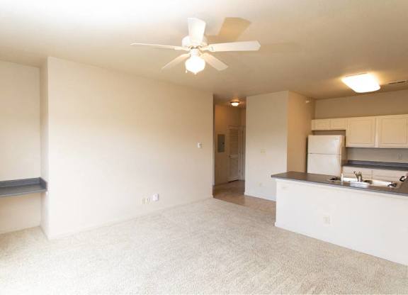 A room with a ceiling fan and a kitchenette.