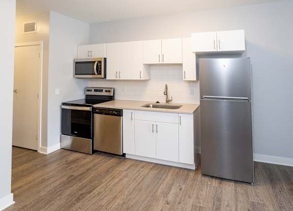 A kitchen with a stainless steel refrigerator, microwave, oven, and sink.