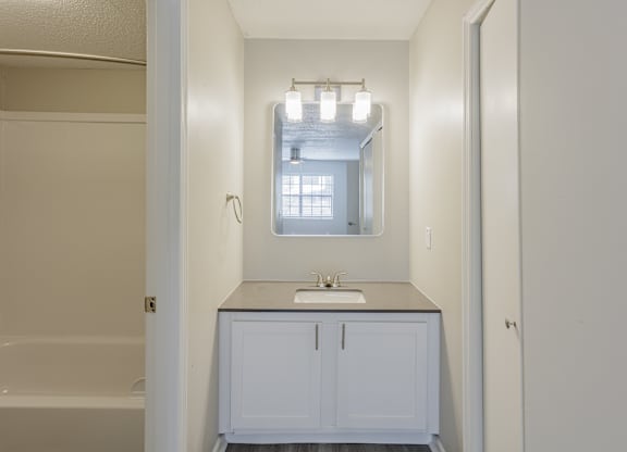 A white bathroom with a sink and a window.