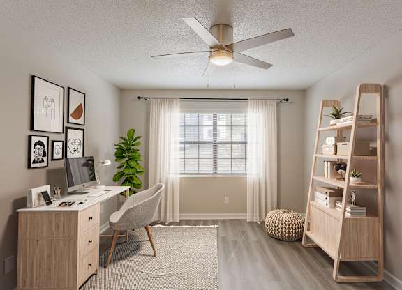 A room with a desk, chair, and a plant.