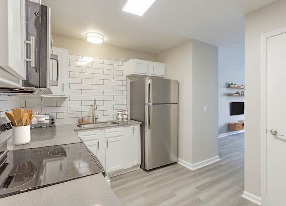 A kitchen with a refrigerator, stove, and sink.