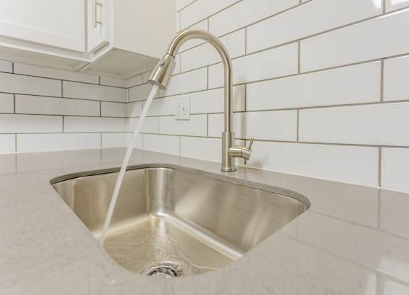 A silver sink with a chrome faucet and a white hose running from the tap.